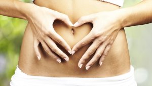 healthy woman doing heart symbol on her belly button at outdoor