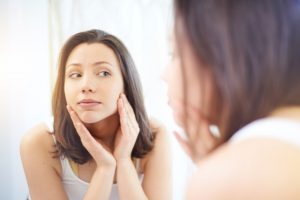 Over the shoulder shot of an attractive young woman looking at her reflection in a mirror