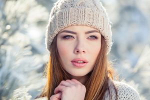 Beautiful winter portrait of young woman in the winter snowy scenery.